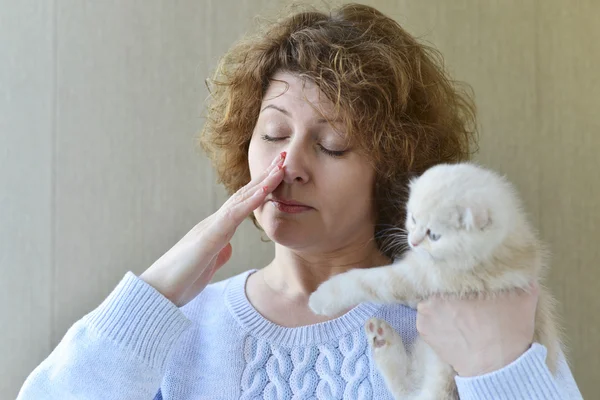 Mulher com alergia está segurando gatinho — Fotografia de Stock