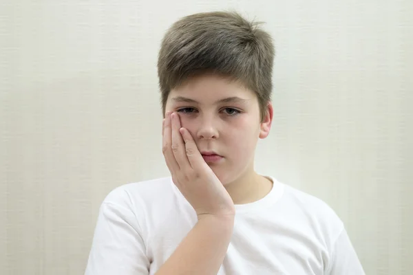 Ragazzo adolescente con un mal di denti su sfondo chiaro — Foto Stock