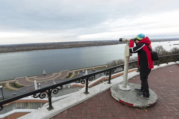 Nizhny Novgorod, Russia - November 11, 2015. Boy looks through binoculars on  Volga River from the lookout — Stock Photo, Image