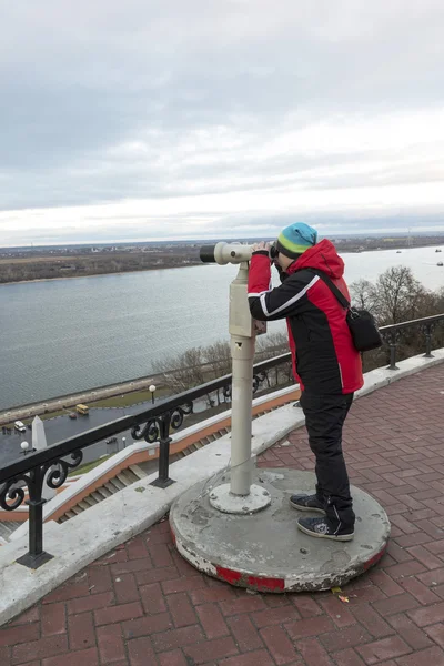 Nizhny Novgorod, Russia - November 11, 2015. Boy looks through binoculars on  Volga River from the lookout — Stock Photo, Image