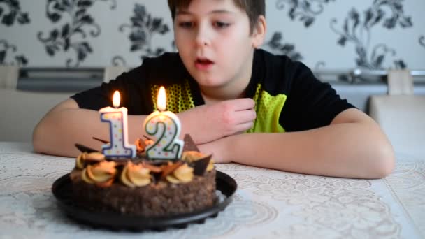 El chico soplando velas de pastel con el número doce — Vídeos de Stock