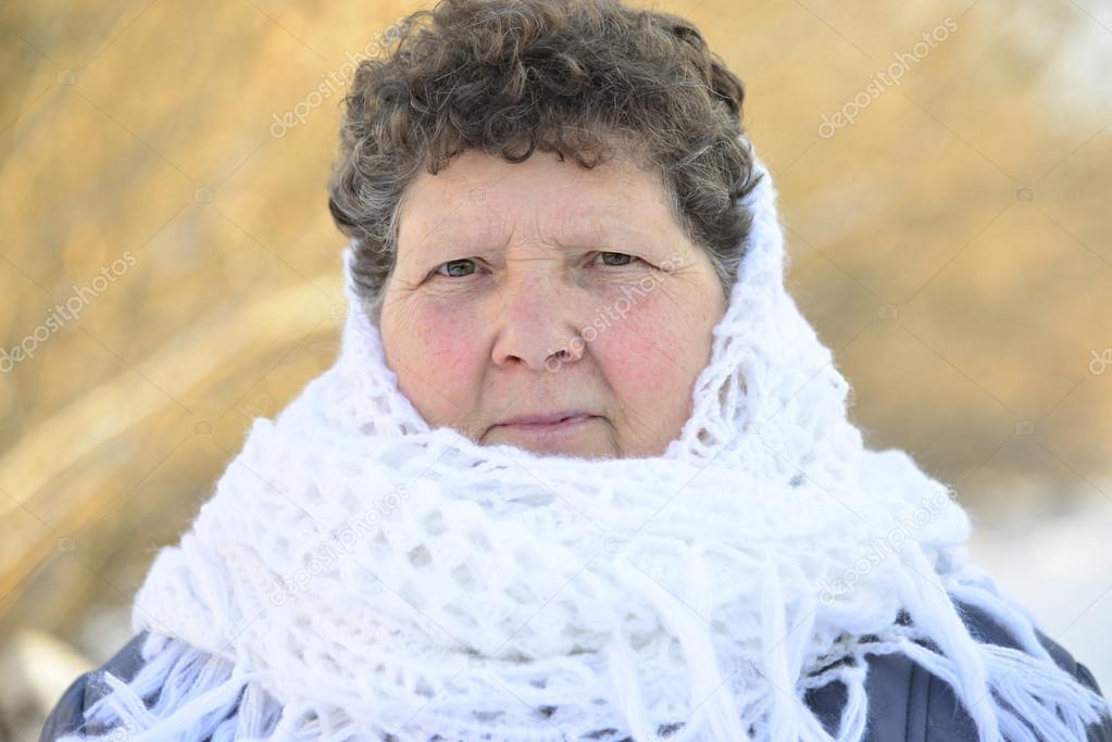 elderly woman in  white knitted shawl on her head