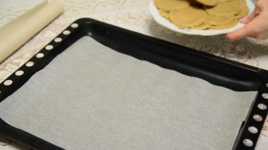 Kadın çiğ yulaf ezmeli kurabiye fırın tepsisine koyar.