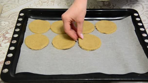 Mujer pone galletas de avena crudas en una bandeja para hornear — Vídeo de stock