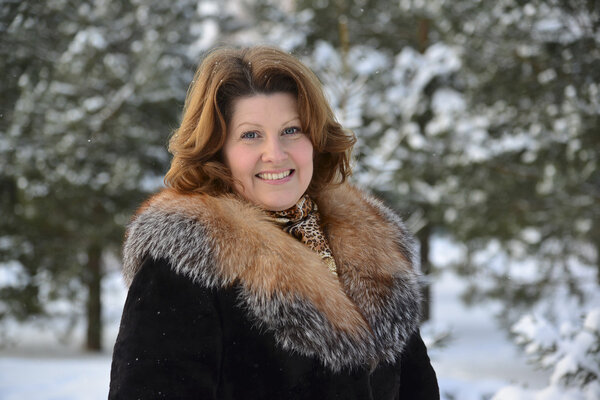 Позитивная женщина средних лет в зимнем лесу
