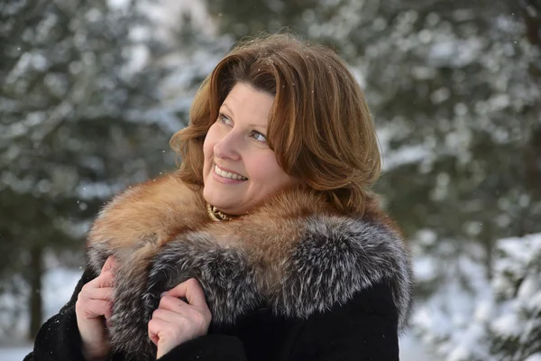 Positive middle-aged woman in  winter forest — Stock Photo, Image