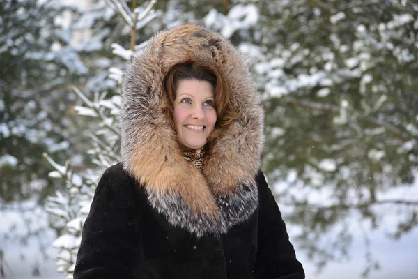 Mujer positiva de mediana edad en abrigo de piel en el parque de invierno — Foto de Stock