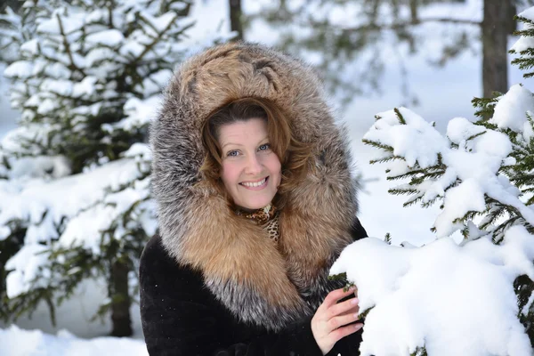 Femme d'âge moyen positive en manteau de fourrure au parc d'hiver — Photo