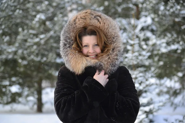 Mujer positiva de mediana edad en abrigo de piel en el parque de invierno — Foto de Stock