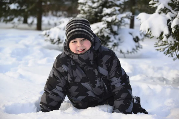 Teen pojke sitter på snö i vinter skogen — Stockfoto