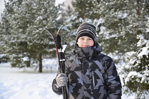 Tini fiú, egy fenyves erdőben, télen sílécek — Stock Fotó