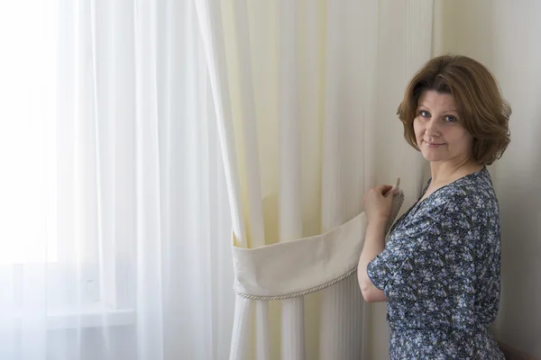 Donna appendere le tende bianche alla finestra — Foto Stock