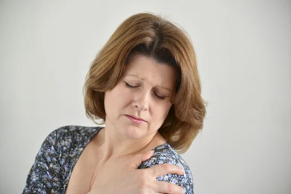 Mujer con dolor en el hombro sobre fondo claro — Foto de Stock