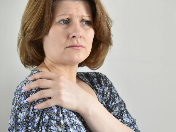 Frau mit Schmerzen in der Schulter auf hellem Hintergrund — Stockfoto