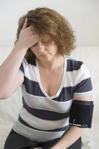 Mujer con dolor de cabeza mide la presión arterial — Foto de Stock