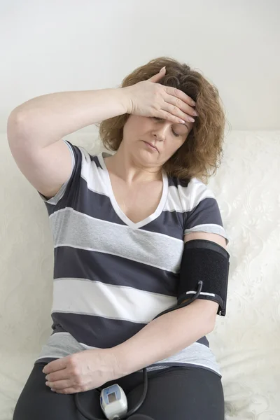 Mujer con dolor de cabeza mide la presión arterial —  Fotos de Stock