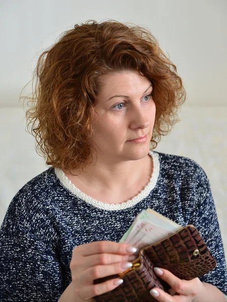 Вдумчивая русская женщина вытаскивает из кошелька рубли — стоковое фото