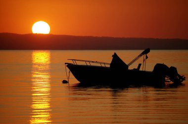 Güneşin doğuşundaki bir teknenin silueti