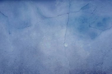 Açık mavi boyayla boyanmış eski bir evin beton duvarı.