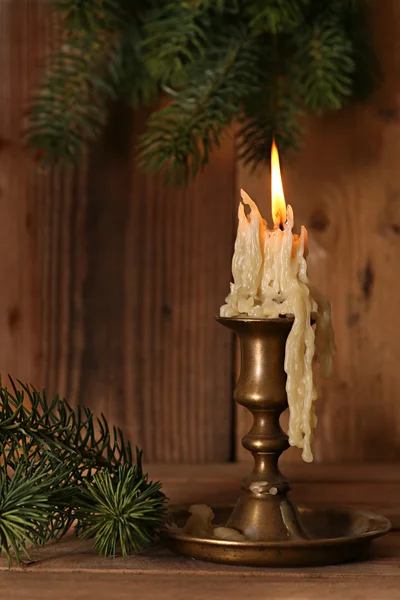 Burning old Candle Vintage Bronze candlestick on wooden background. Spruce branches. Christmas . — Stock Photo, Image