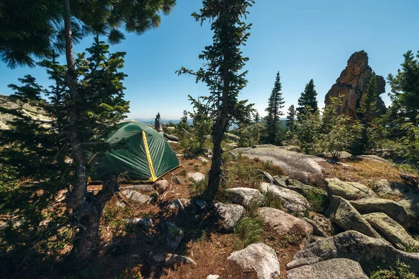 Tent among mountains and woods on a hill.