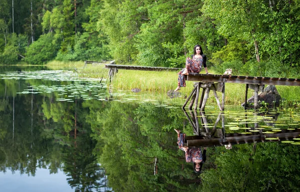 Брюнетка жінка на озері мосту з відображенням води — стокове фото
