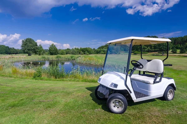 Carro de golfe perto da lagoa de água — Fotografia de Stock