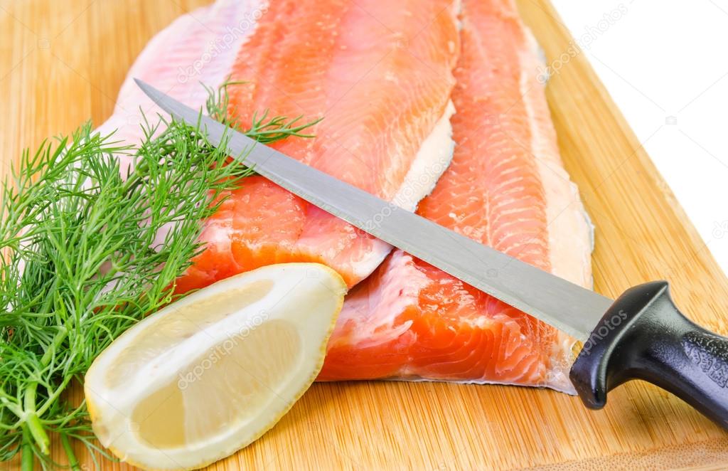 Closeup for trout fish fillet with knife on a kitchen board