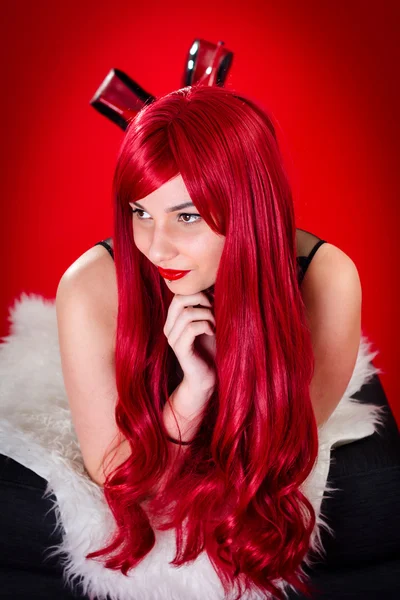 Belles jeunes femmes aux cheveux roux avec un fond rouge — Photo