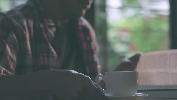 Mann liest ein Buch und trinkt Kaffee — Stockvideo