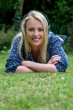 Sarışın kız Earphones ile çim üzerinde yalan