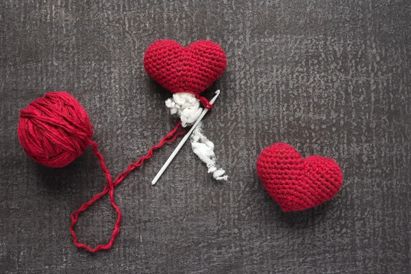 Crocheted red hearts on a grunge board — Stock Photo, Image