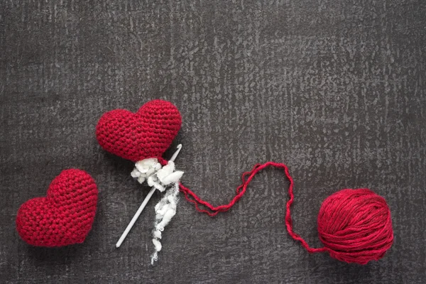 Crocheted red hearts on a grunge board — Stock Photo, Image