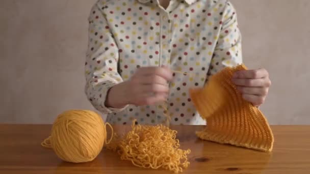 Женщина распутывает жёлтый шарф — стоковое видео