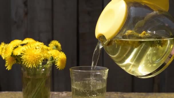 Thee met paardebloemen in een glas gieten — Stockvideo