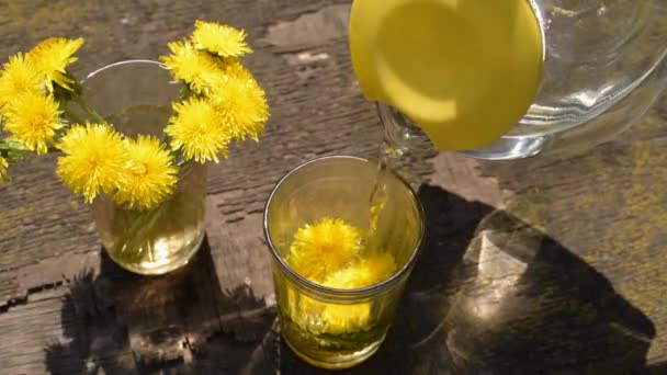 Pouring water into a glass with dandelions — Stock Video