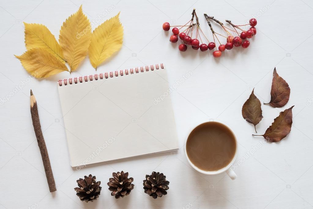 Attributes of autumn, coffee and notebook on a white board
