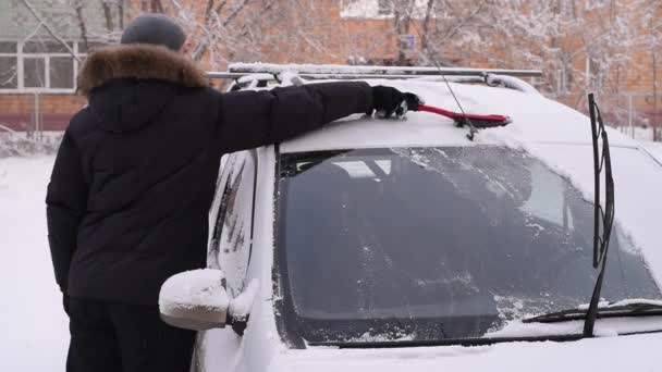 Un homme nettoie la voiture de la neige — Video