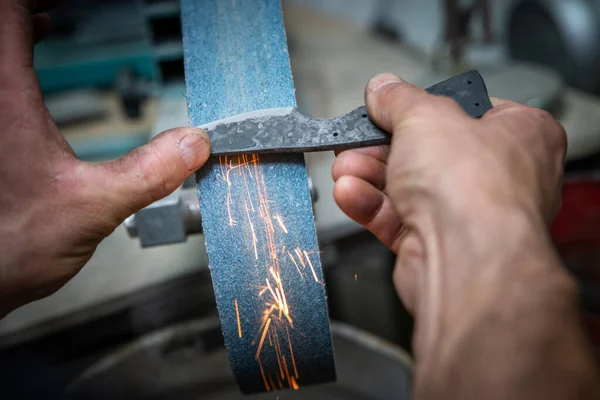 two man hands are manufacturing a steel knife