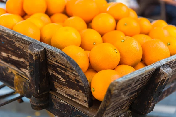 Свежие апельсины на винтажной деревянной тележке — стоковое фото