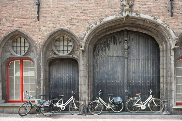 Bicycles leaning against old wooden door — Stock Photo, Image