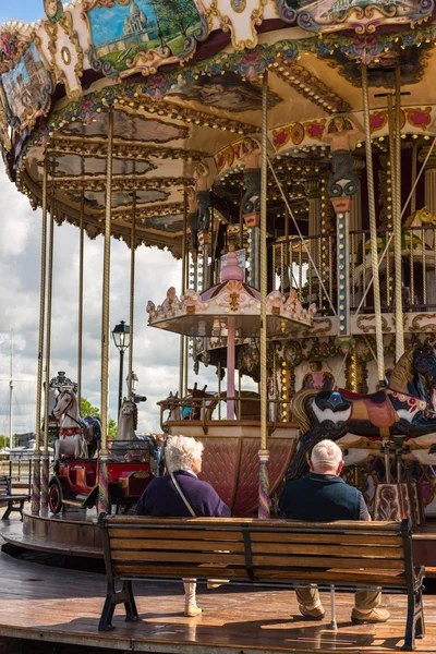 Pary staruszków siedzi w pobliżu carousel — Zdjęcie stockowe