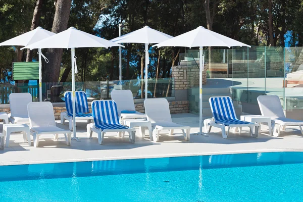 Hotel zwembad stoelen met uitzicht op zee. — Stockfoto