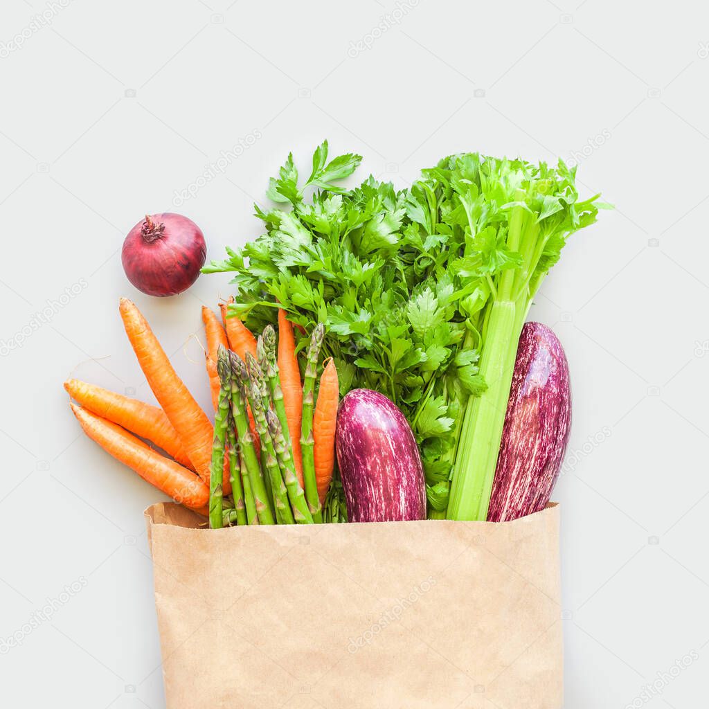 Fresh organic vegetables in eco craft paper shopping bag  in flat lay, top view with copy space on gray background. Sustainable lifestyle. Zero waste, plastic free, care package, donation concept