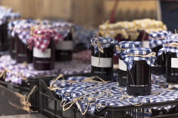 Many preserving jars with dark jam in a market — Stock Photo, Image