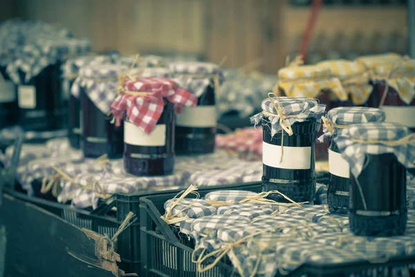 Muchos tarros de conservación con mermelada oscura en un mercado —  Fotos de Stock