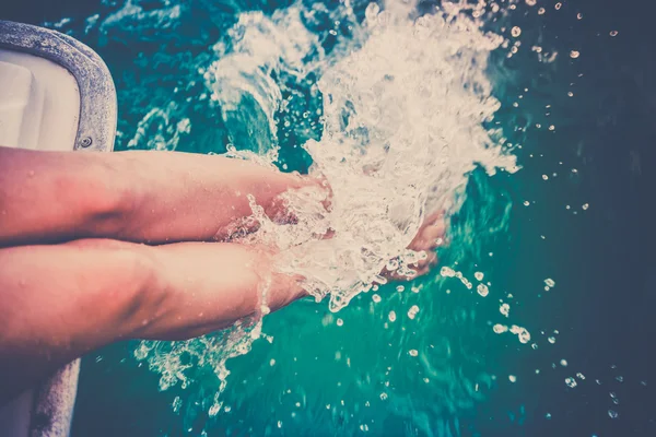 Frauenbeine spritzen Meerwasser von einer Segeljacht — Stockfoto