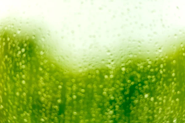 Gouttes d'eau sur une surface en verre dans des tons vert vif — Photo