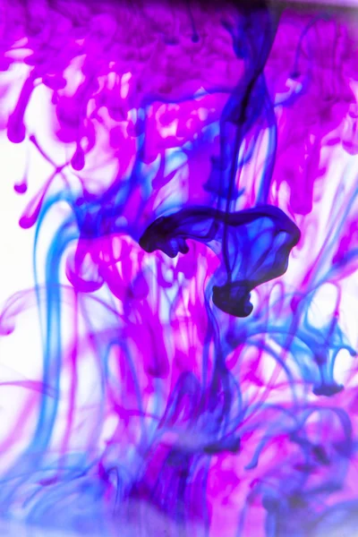 Blaue und violette Flüssigkeit im Wasser, die abstrakte Formen bildet — Stockfoto