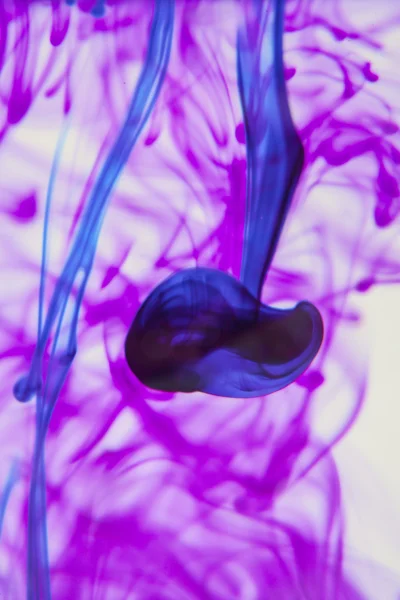 Liquide bleu et violet dans l'eau faisant des formes abstraites — Photo